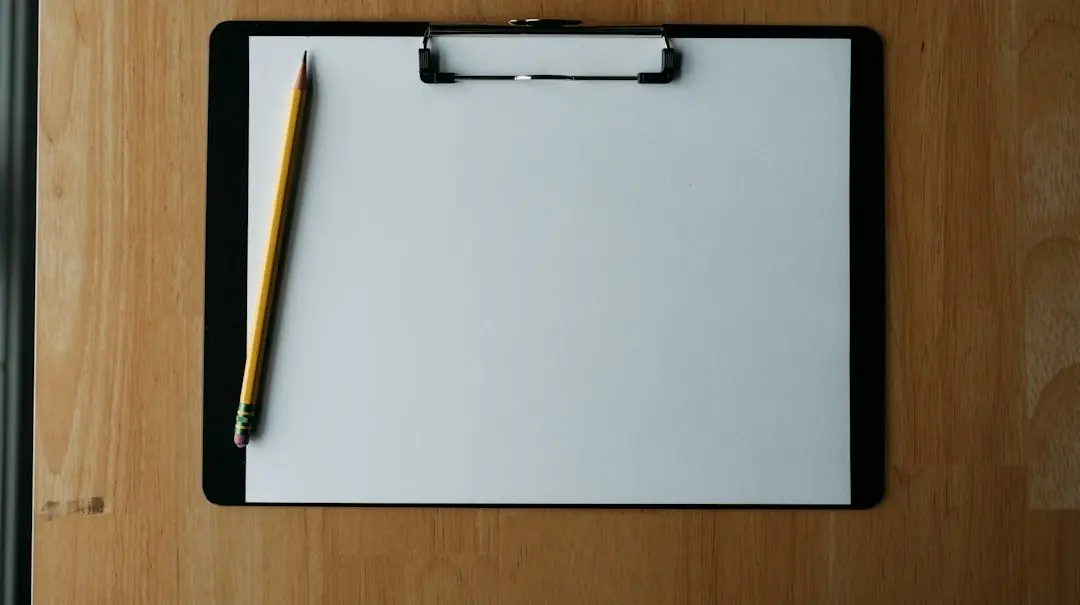 A blank clipboard and a pencil on a wooden desk, ready to compare IPTV services