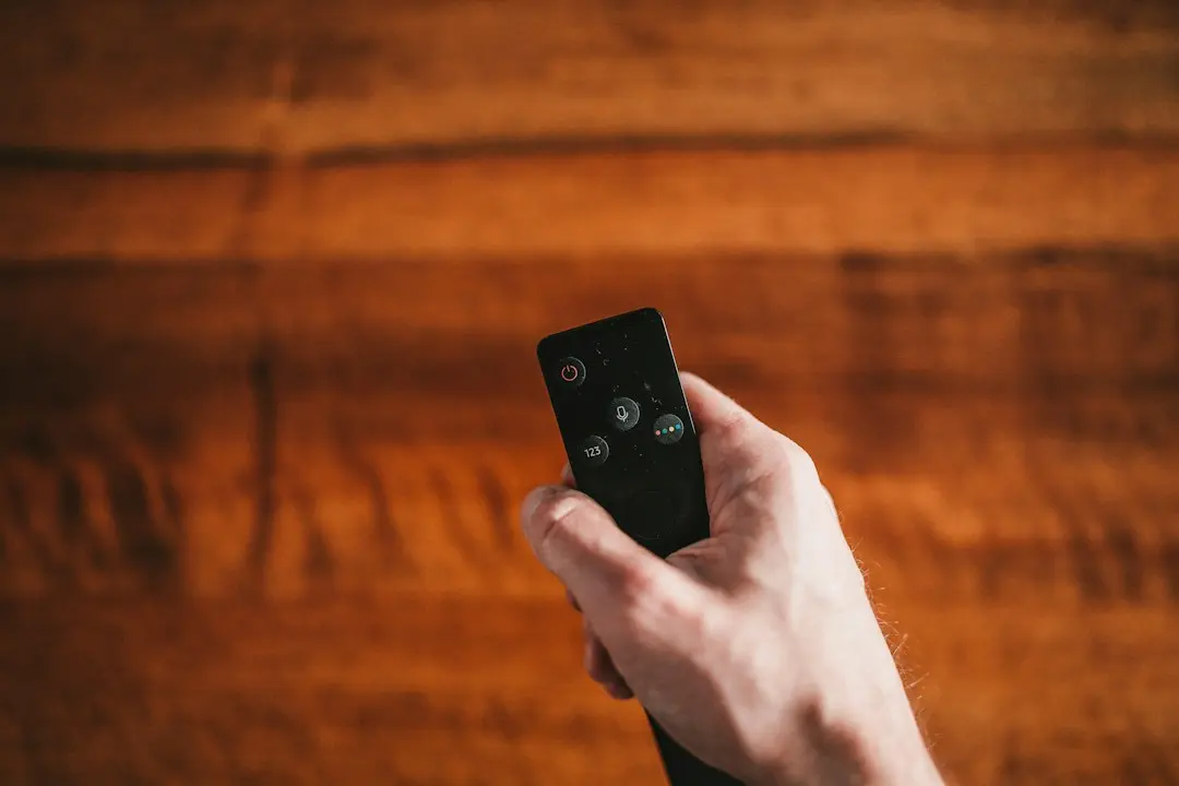 A hand pointing a streaming remote over a wooden table, ready to set up GoFluxTv IPTV for Firestick