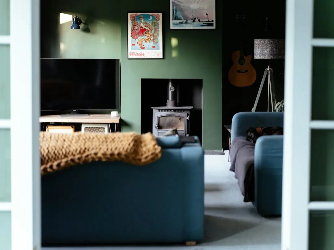 A green living room with a TV on a low stand, a wood stove and a blue sofa, the kind of setup GoFluxTv runs on